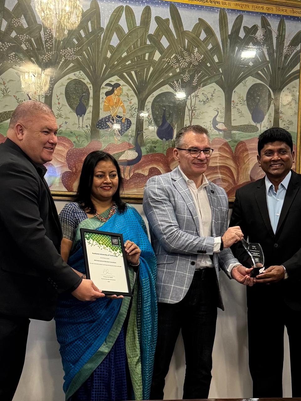 The moment of receiving the AUT Best Performing Agent award, with a trophy being handed over and a certificate held by four people