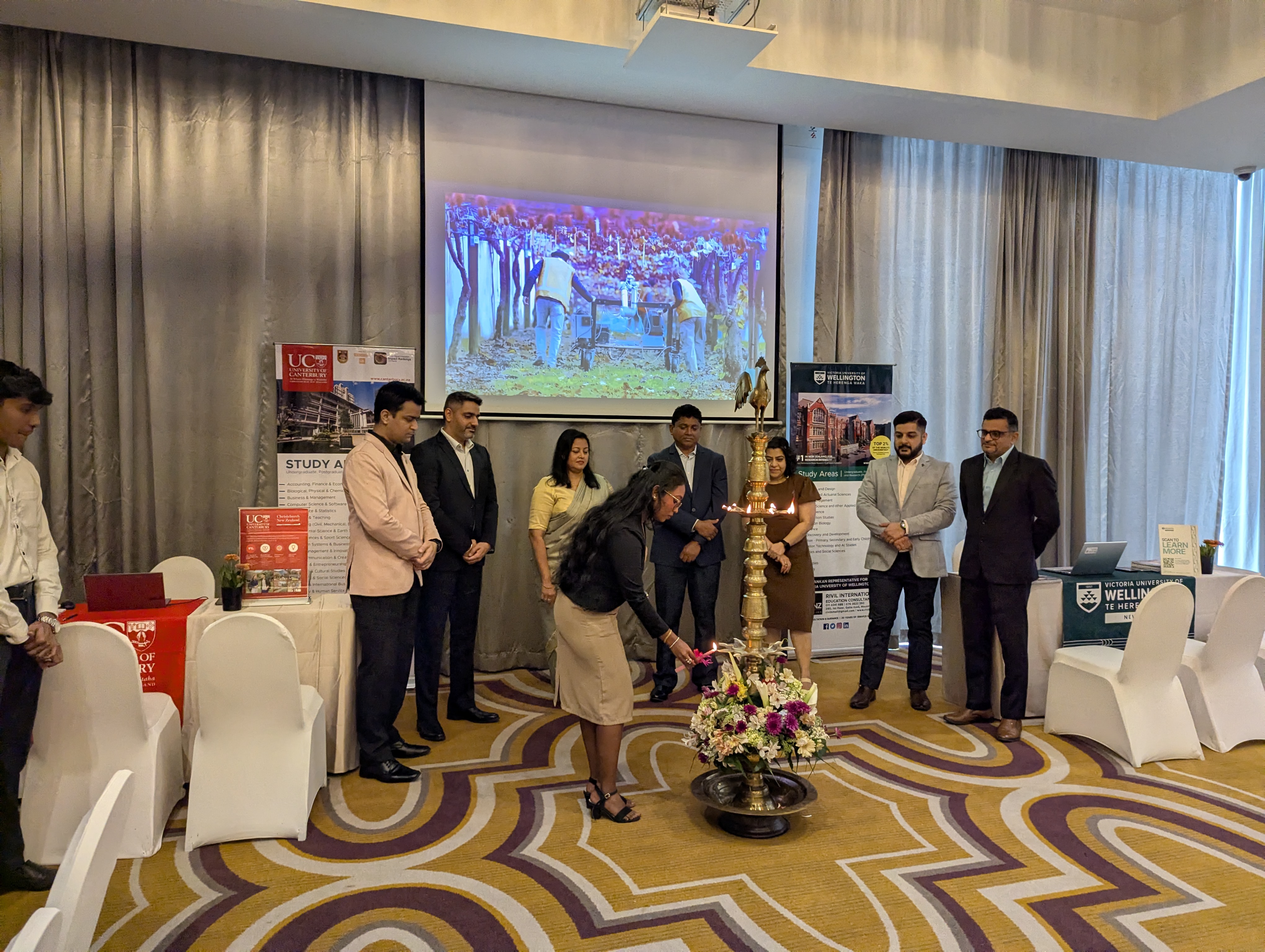 Traditional oil lamp lighting ceremony opening a New Zealand education event, with University of Canterbury and Victoria University of Wellington banners visible